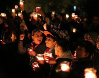 This is a picture of Girl and Boy Scouts laughing and holding candles in celebration of Earth Hour.