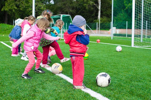 This is a picture of children playing soccer in their fun winter clothes.