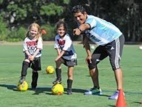 This is a picture of two young girls and a soccer instructor on a soccer field.