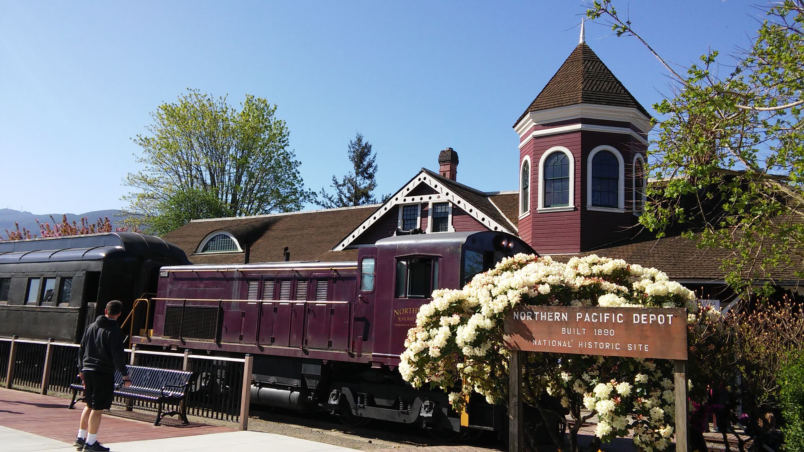 This is a picture of the Historic Snoqualmie Train Depot with flowers in front of it.